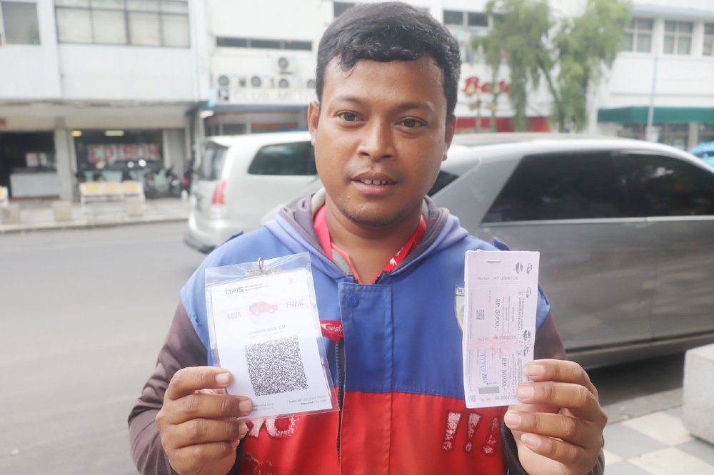 CANGGIH: Seorang jukir menunjukkan voucer dan kode QRIS di Jalan Tunjungan.
