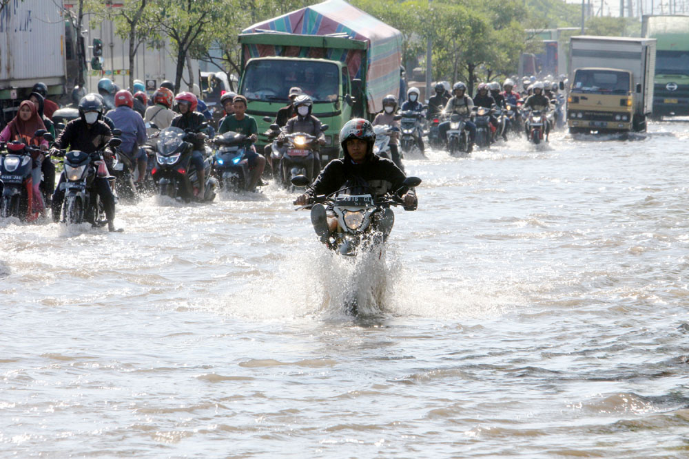 TERPUTUS: Sejumlah pengendara motor nekat menerobos banjir yang menggenangi kawasan Jalan Tambak Oso Wilangun, Surabaya, meskipun ada beberapa yang mendorong motornya karena mogok, Selasa (6/2).