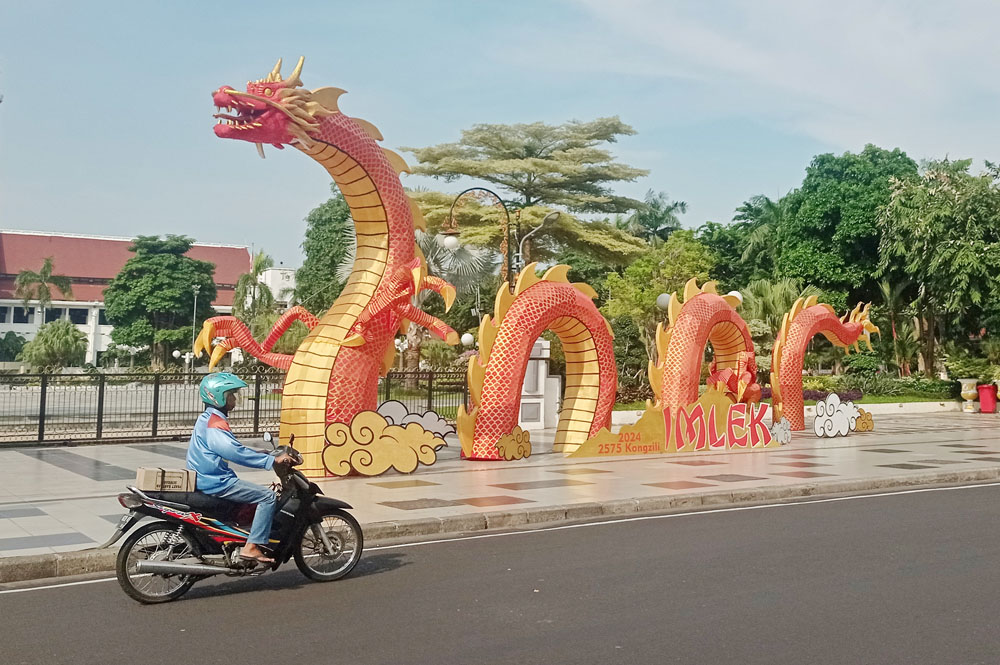 SAMBUT IMLEK: Pengendara kendaraan bermotor melintas tak jauh dari ornamen Naga untuk menyambut Tahun Baru Imlek yang terpasang didepan Balaikota Surabaya, Kamis (8/2).