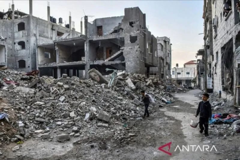 Dua bocah Palestina di Gaza berjalan di antara reruntuhan bangunan yang hancur dibombardir militer Israel.