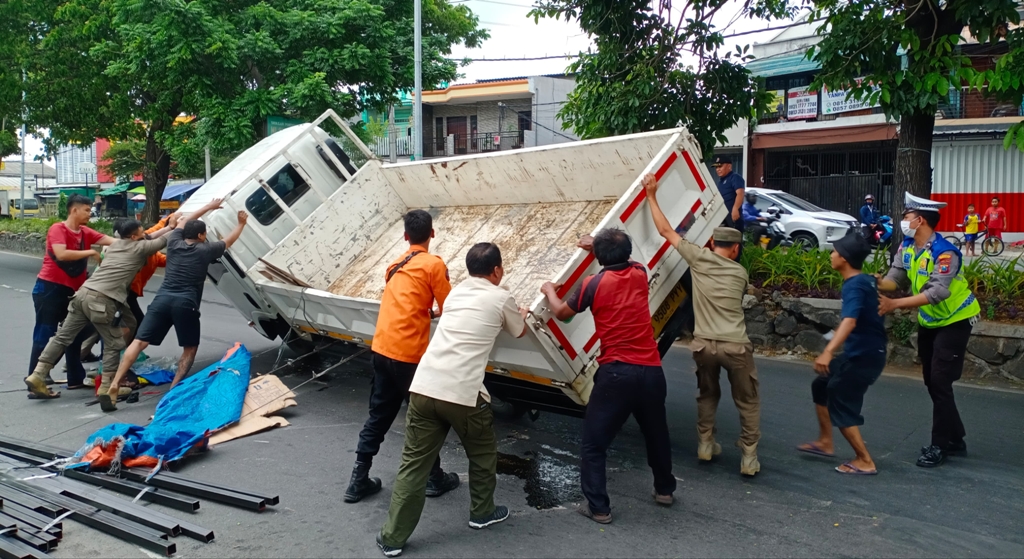 APES: Petugas mengevakuasi truk yang terguling di Jalan Sukomanunggal, Surabaya.