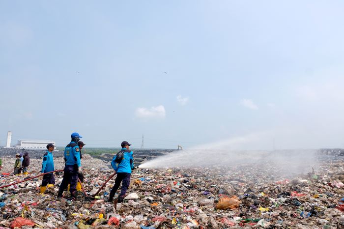 CEGAH BAU: Petugas menyemprot sampah di TPA Benowo. Sehari, produksi sampah di Surabaya bisa capai 1.500 ton. (SURYANTO/RADAR SURABAYA)