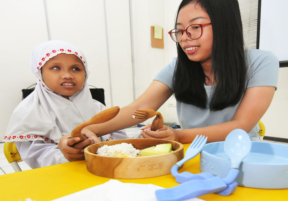 DIDESAIN KHUSUS: Aulia (kiri) disabilitas netra mencoba set alat makan yang dilengkapi huruf braille karya Alicia Secsionia.
