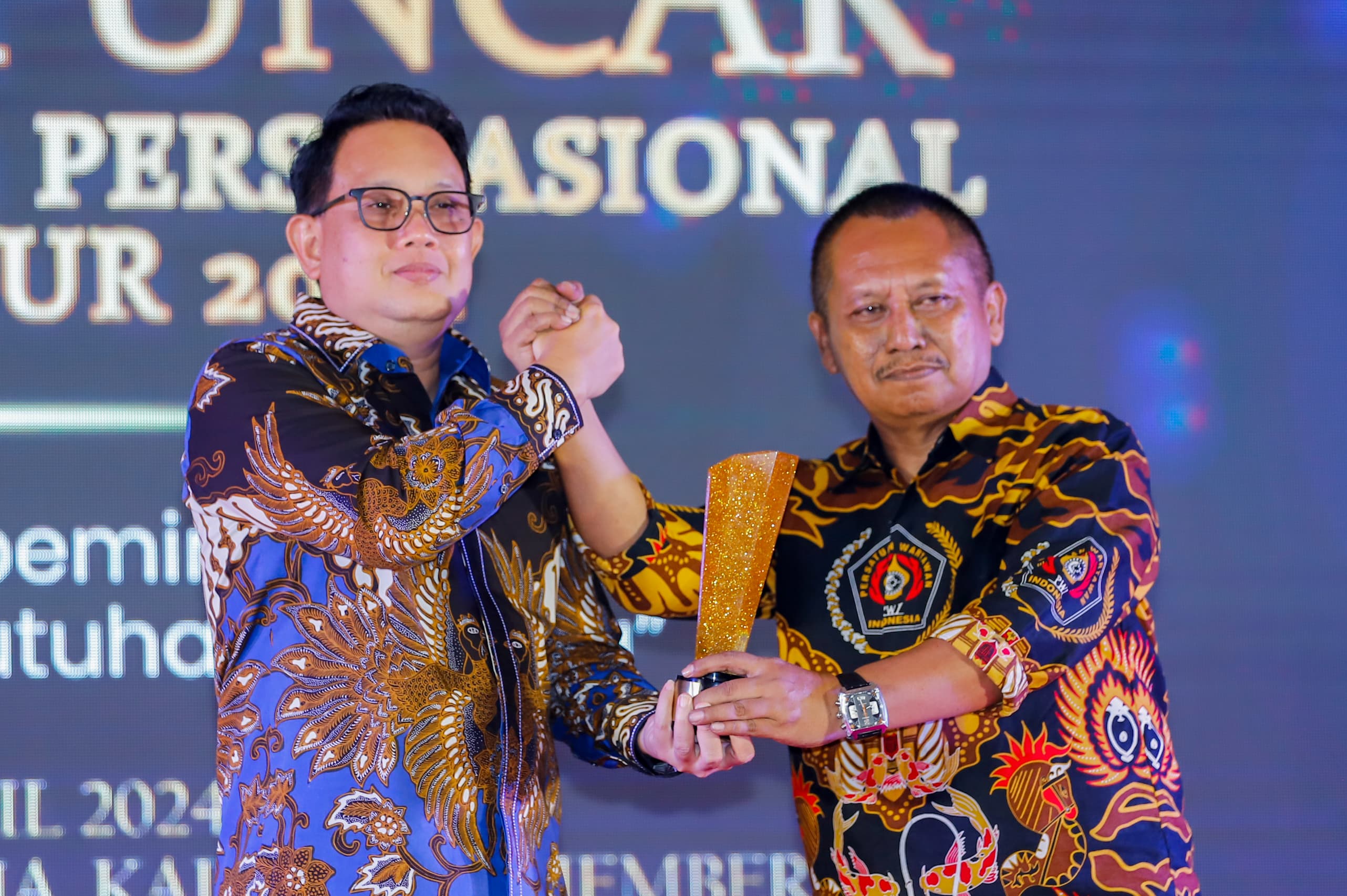 Pj Gubernur Jatim Adhy Karyono menerima piala PWI Jatim Award 2024 dari Ketua PWI Jatim Luthfil Hakim.