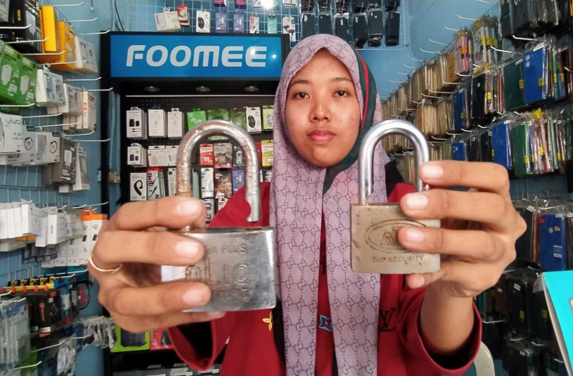 Yunita menunjukkan gembok yang dijebol pelaku pencurian (MAHRUS/RADAR SURABAYA).