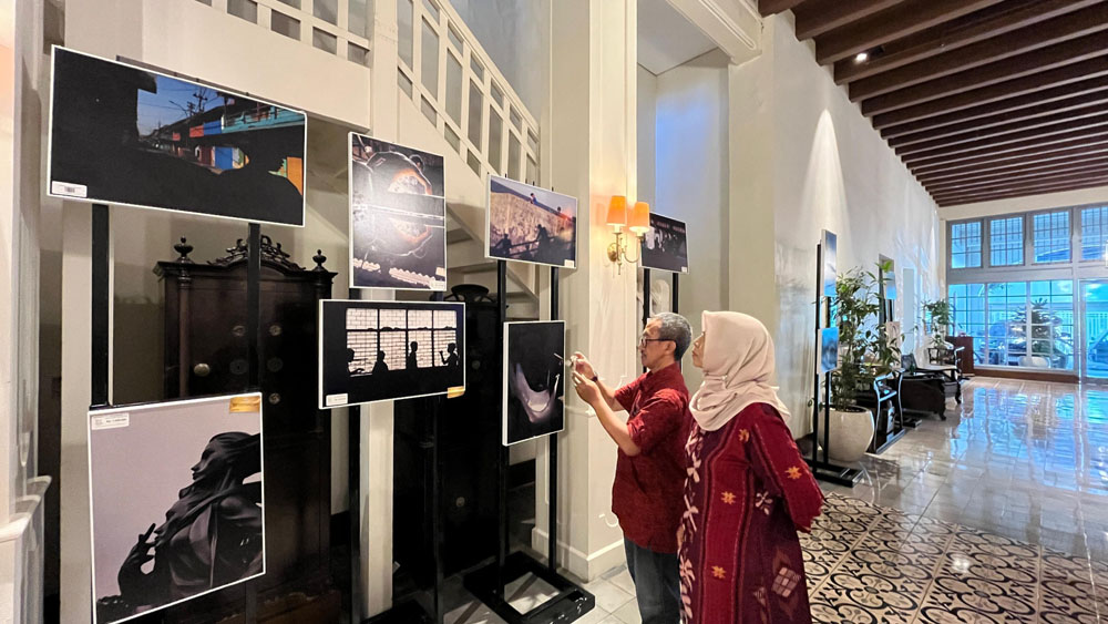 TERAMPIL: Dua tamu Kokoon Hotel Surabaya melihat hasil karya fotografi anak-anak disabilitas dari Kampung Anak Negeri.