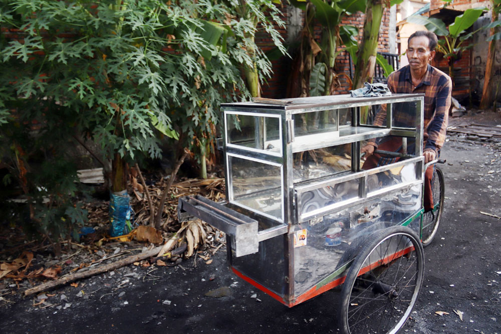 Damhudji saat mengayuh gerobak sate kelincinya keliling di kawasan Kalijudan Surabaya.