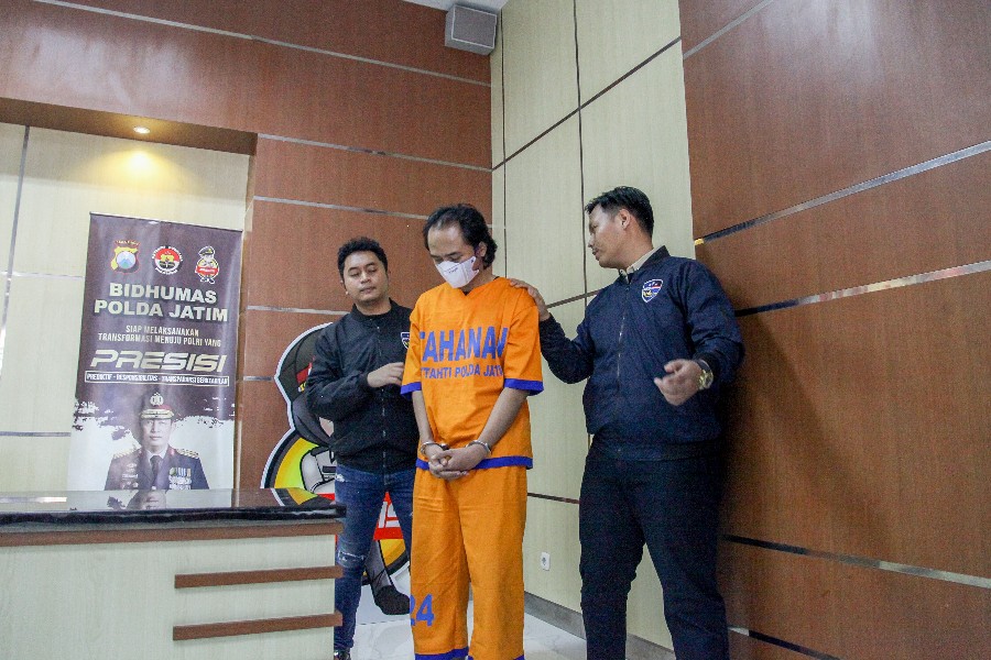 Petugas menunjukkan Anggriawan, tersangka kasus penyebaran konten pornografi yang berhasil diamankan di Mapolda Jatim, Jalan Ahmad Yani, Surabaya, Kamis (6/6).