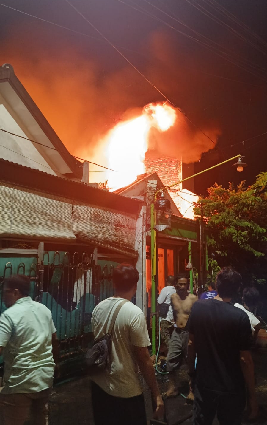 MENYALA: Warga berupaya memadamkan api dengan alat seadanya di rumah Jalan Simo Sidomulyo IX, Surabaya, Rabu (12/6) malam.