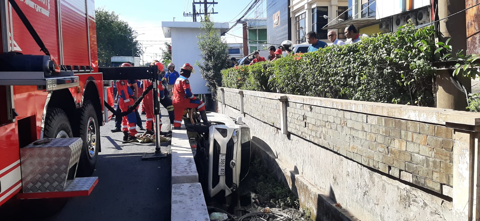 Tim Rescue DPKP Surabaya berupaya mengevakuasi mobil yang terperosok di selokan Jalan Kali Rungkut, Surabaya Rabu (19/6). (MAHRUS/RADAR SURABAYA)