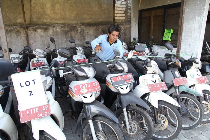 LOT 2: Petugas memeriksa kondisi kendaraan bermotor roda dua aset Pemkot Surabaya yang akan dilelang di gudang di kawasan Dupak Rukun, Surabaya, Selasa (25/6). (SURYANTO/RADAR SURABAYA)