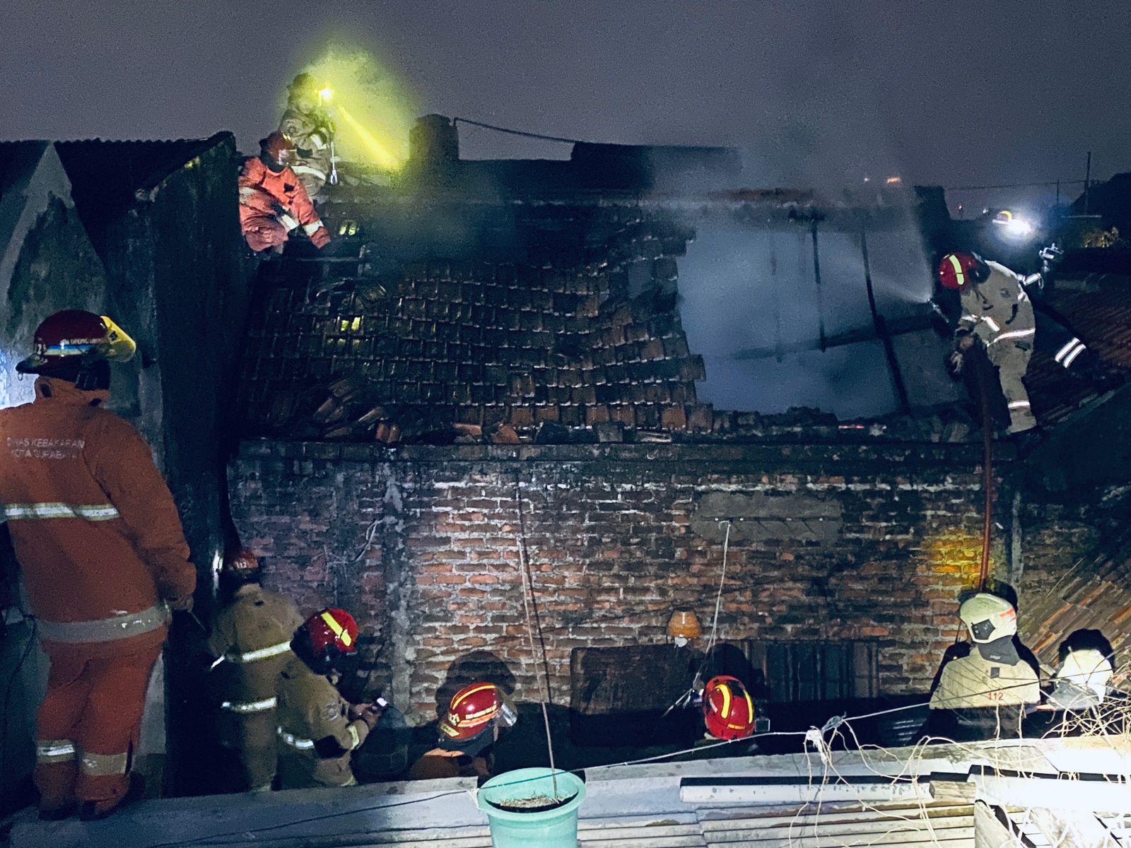 Petugas DPKP Surabaya memadamkan api yang membakar rumah warga di Jalan Wonorejo III, Surabaya. Bagian atap rumah terbakar diduga api berasal dari dinding. (IST)