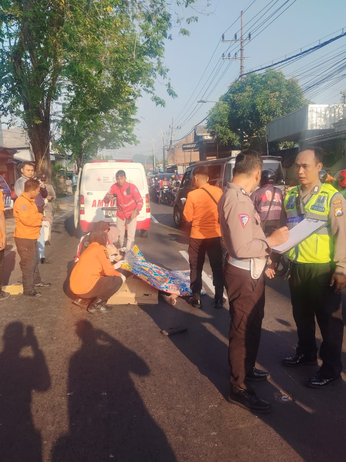 Petugas mengevakuasi mayat Yulfa Andria P yang tertabrak truk trailer di Jalan Mastrip, Surabaya, Selasa (9/7). (IST)