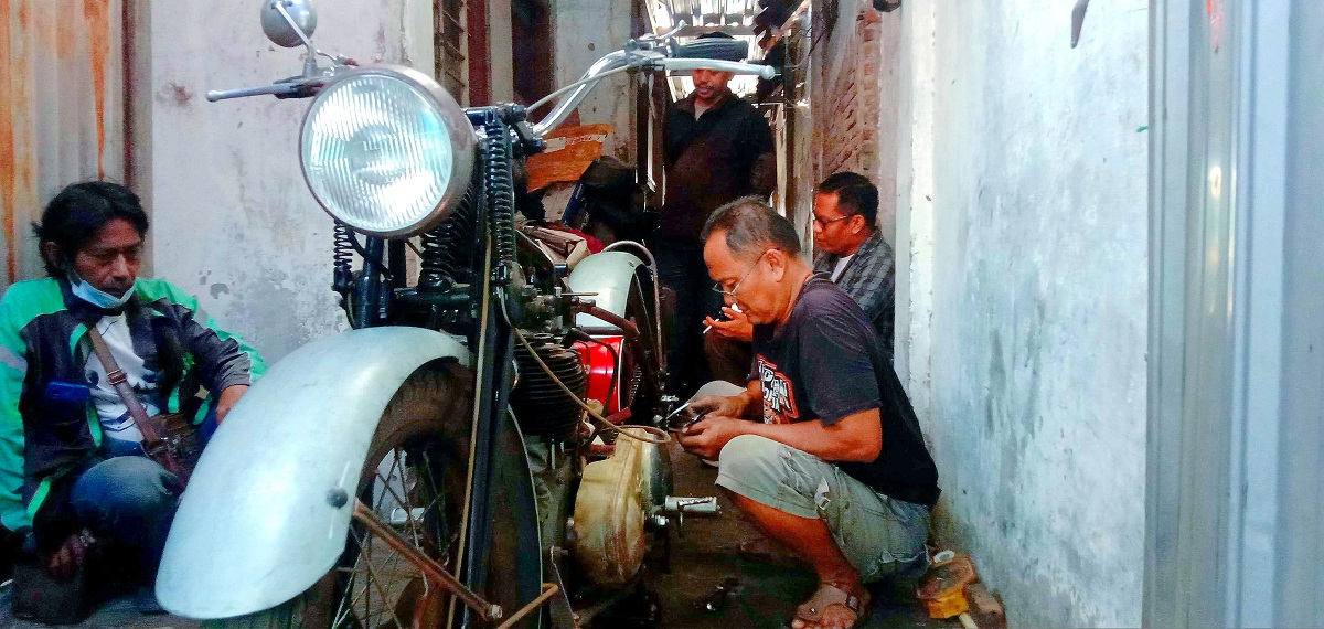 BERAWAL DARI BALI: Zamrony atau biasa disapa Cak Zam (kanan) saat menggarap motor tua milik penghobi.