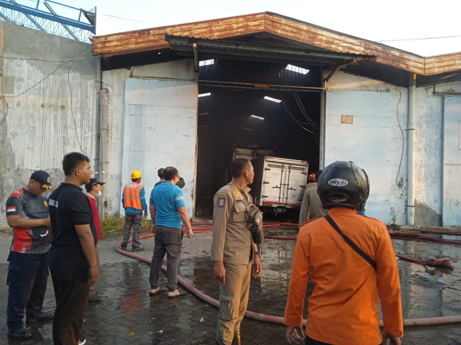 Petugas DPKP Surabaya dibantu Polsek Asemrowo memadamkan api yang membakar salah satu gudang di Pergudangan Margomulyo Permai, Surabaya. (IST)