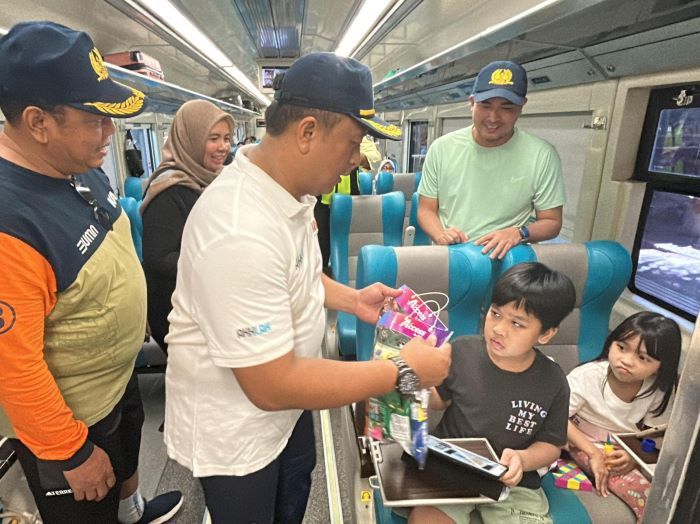 MENYAPA: Petugas KAI Daop 8 Surabaya saat memberikan souvenir kepada penumpang anak-anak baik di stasiun maupun di dalam gerbong KA. (IST)