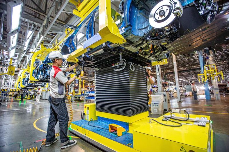 Seorang mekanik sedang memasang parts di pabrikan mobil di Thailand.