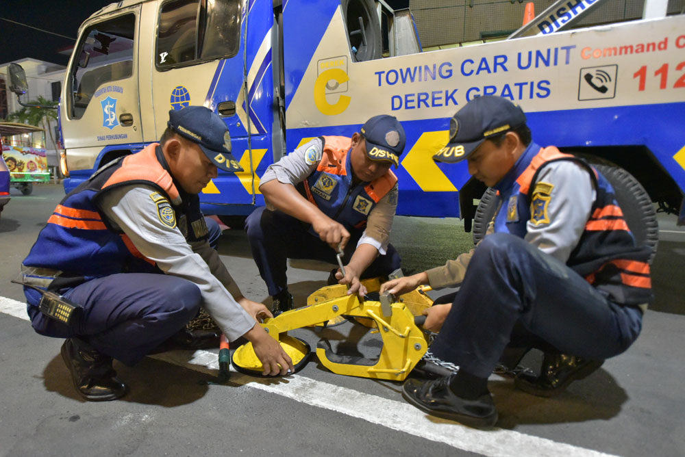 Petugas Dishub Surabaya menyiapkan derek dan gembok mobil untuk melakukan penindakan parkir liar.