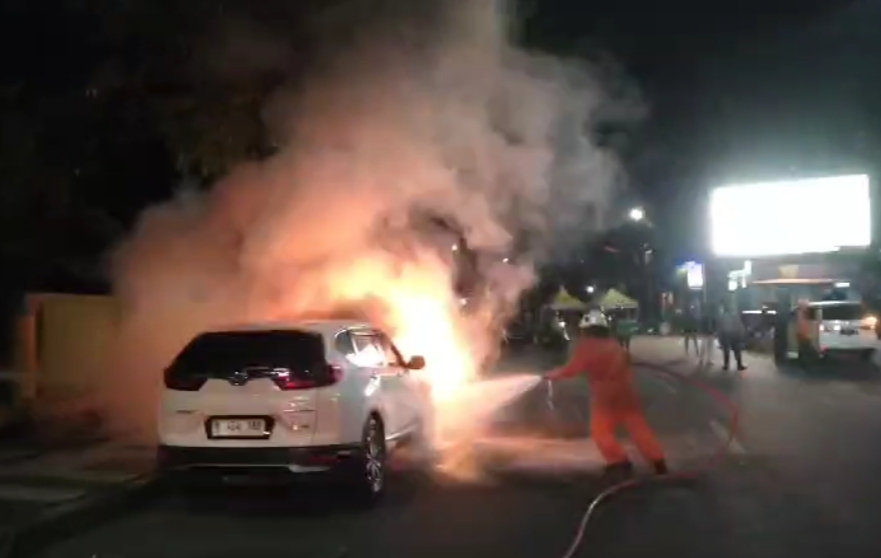 Petugas DPKP Surabaya melakukan upaya pemadaman kebakaran mobil milik Erwin. (IST)