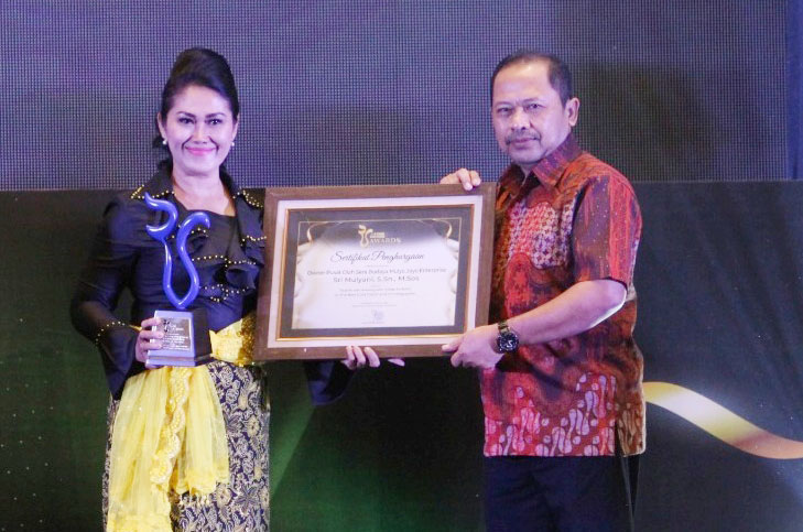 Sri Mulyani menerima piagam dan Piala Radar Surabaya Awards 2024 dari Direktur Radar Surabaya, Lilik Widyantoro.