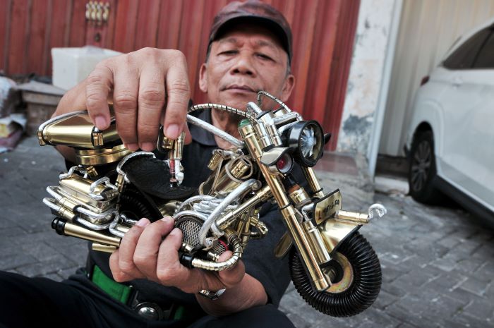MINIATUR: Himawan Suripto, perajin miniatur motor Harley Davidson dari kaleng bekask, menunjukkan hasil karyanya yang sudah dipasarkan, di kediamannya di kawasan Klampis, Surabaya. (ANDY/RSB)