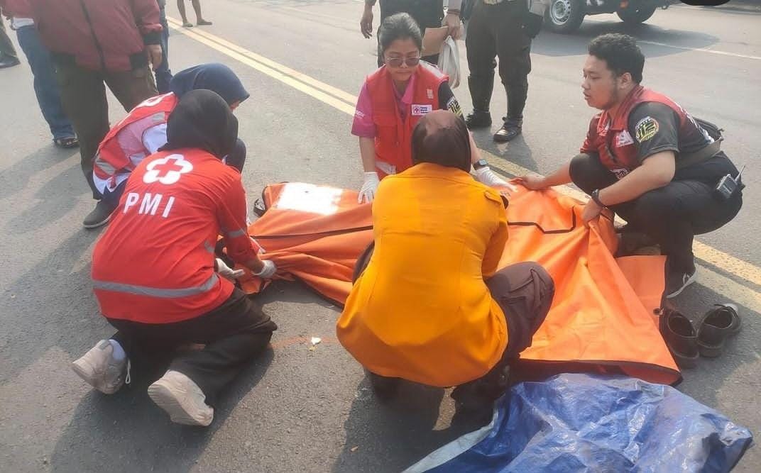 Petugas mengevakuasi jasad Iqbal setelah terlindas truk trailer di Jalan Kalianak, Surabaya. (IST)