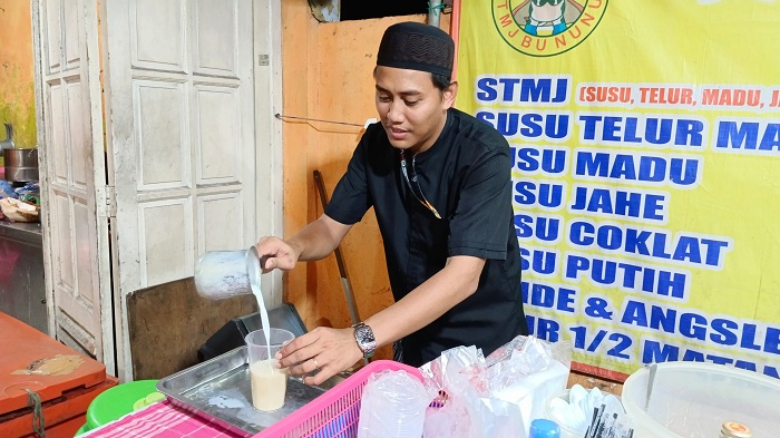 MELAYANI: Putra Bu Nunuk, Rizaldi Santoso Putra, saat meracik di Kedai STMJ Bu Nunuk Ngagel Pojok Surabaya. (DIMAS MAHENDRA/RADAR SURABAYA)
