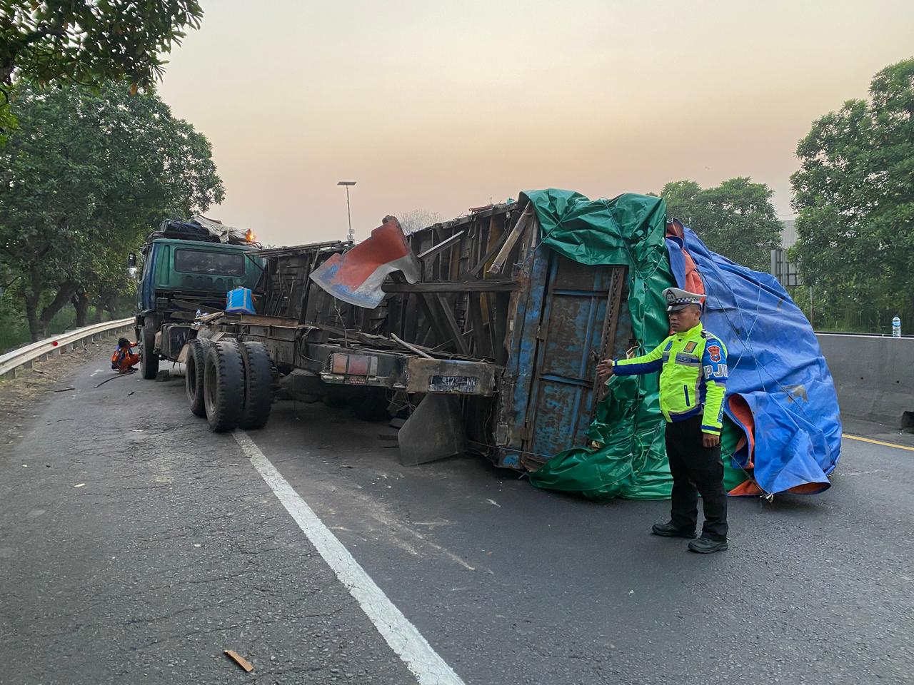 Petugas PJR menunjukkan truk tronton nopol L 9123 NN yang terguling di KM 0+800 Tol Dupak arah Perak, Surabaya, Jumat (26/7). (IST)