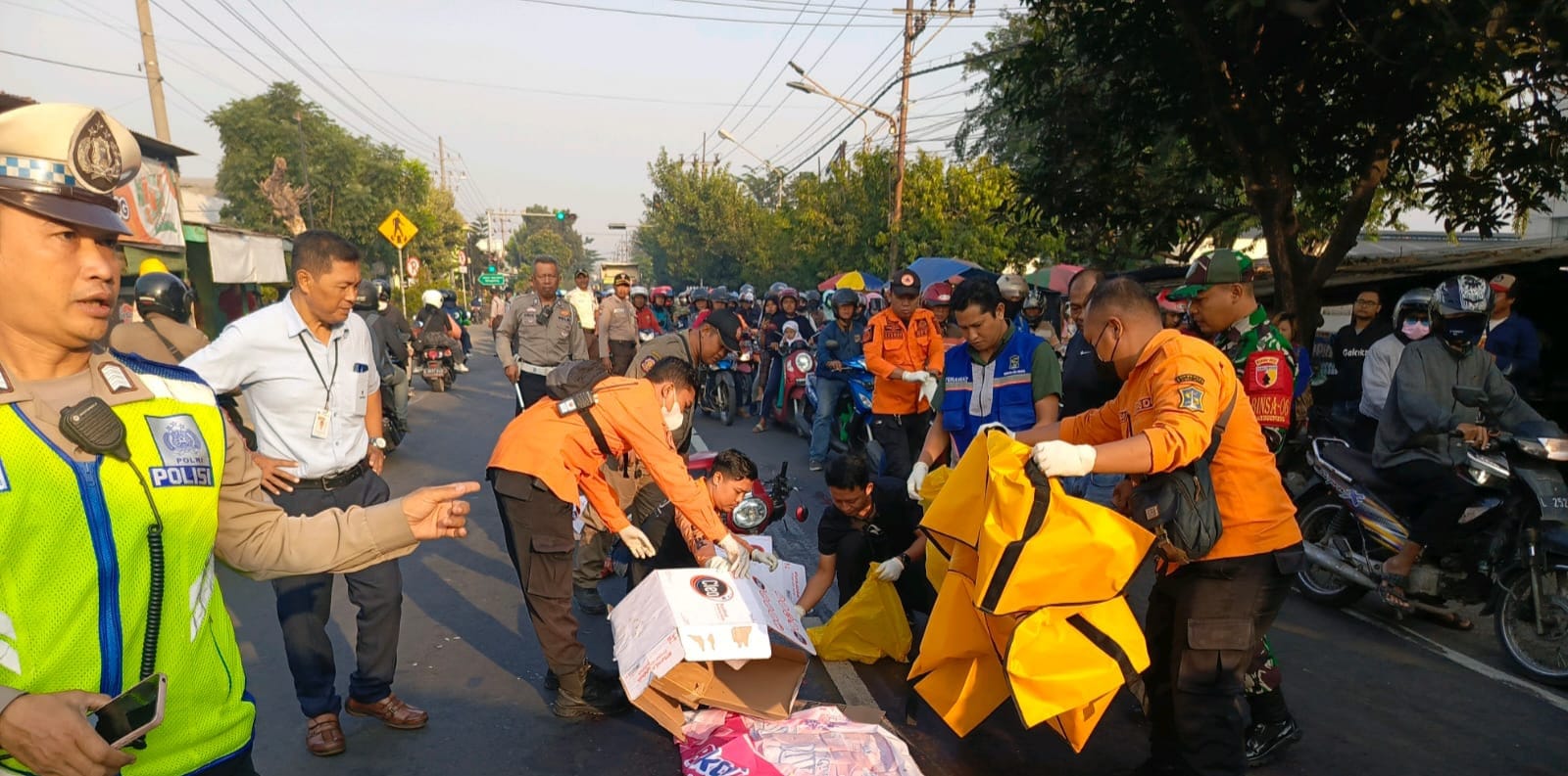 Petugas mengevakuasi mayat korban K, 62, yang tewas terlindas truk gandeng di Jalan Mastrip, Warugunung, Surabaya, Senin (29/7). (IST)