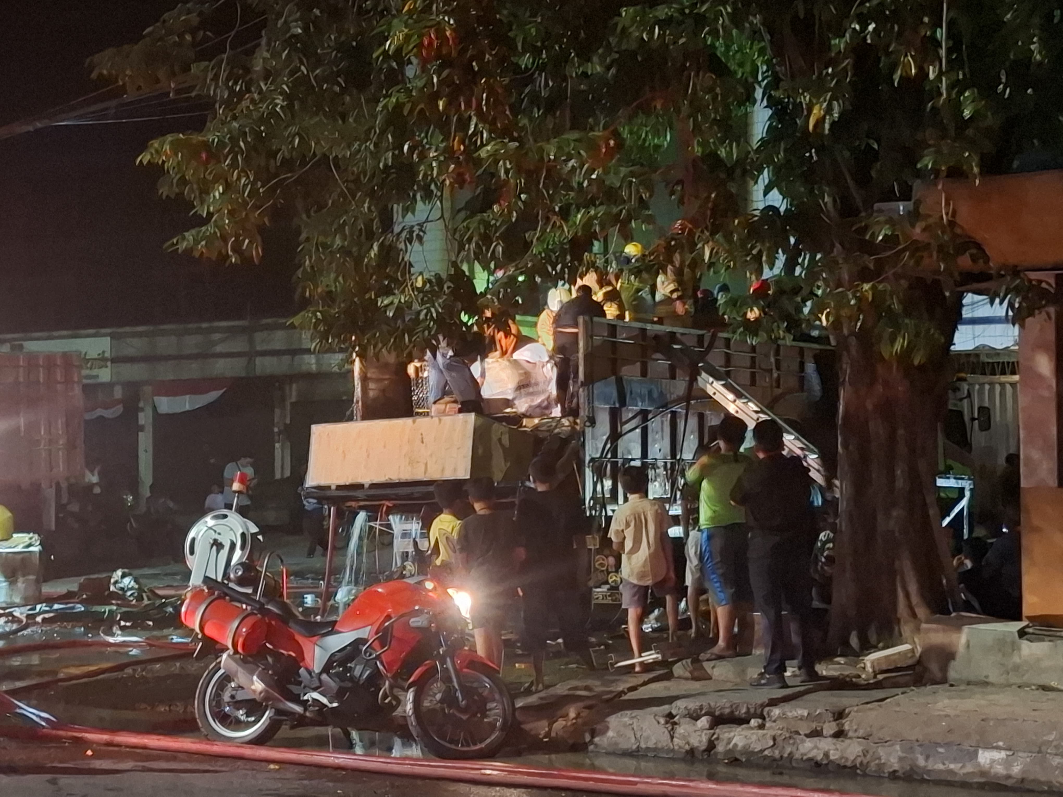 Petugas DPKP Surabaya saat melakukan pemabasahan pada muatan truk ekspedisi yang terbakar di depan ruko Jalan Stasiun Kota, Surabaya. (IST)