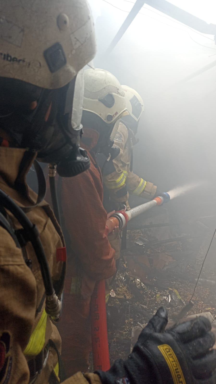 Petugas damkar melakukan pembasahan di rumah yang terbakar di kawasan Bulak Cumpat Surabaya. (IST)