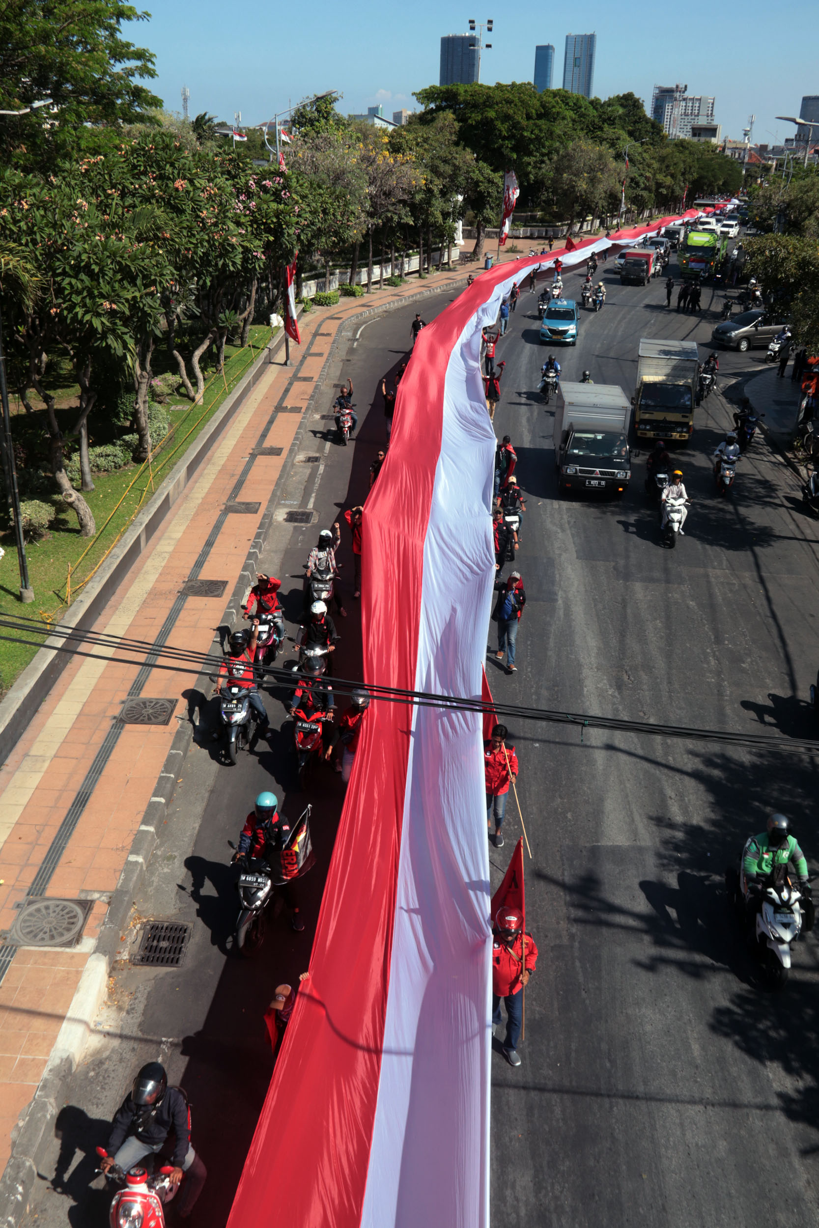 Ratusan sopir truk membentangkan bendera merah putih berukuran raksasa dalam aksi demonstrasinya menuju kantor Gubernur Jatim, Jalan Pahlawan, Surabaya. (ANDY SATRIA/RADAR SURABAYA)