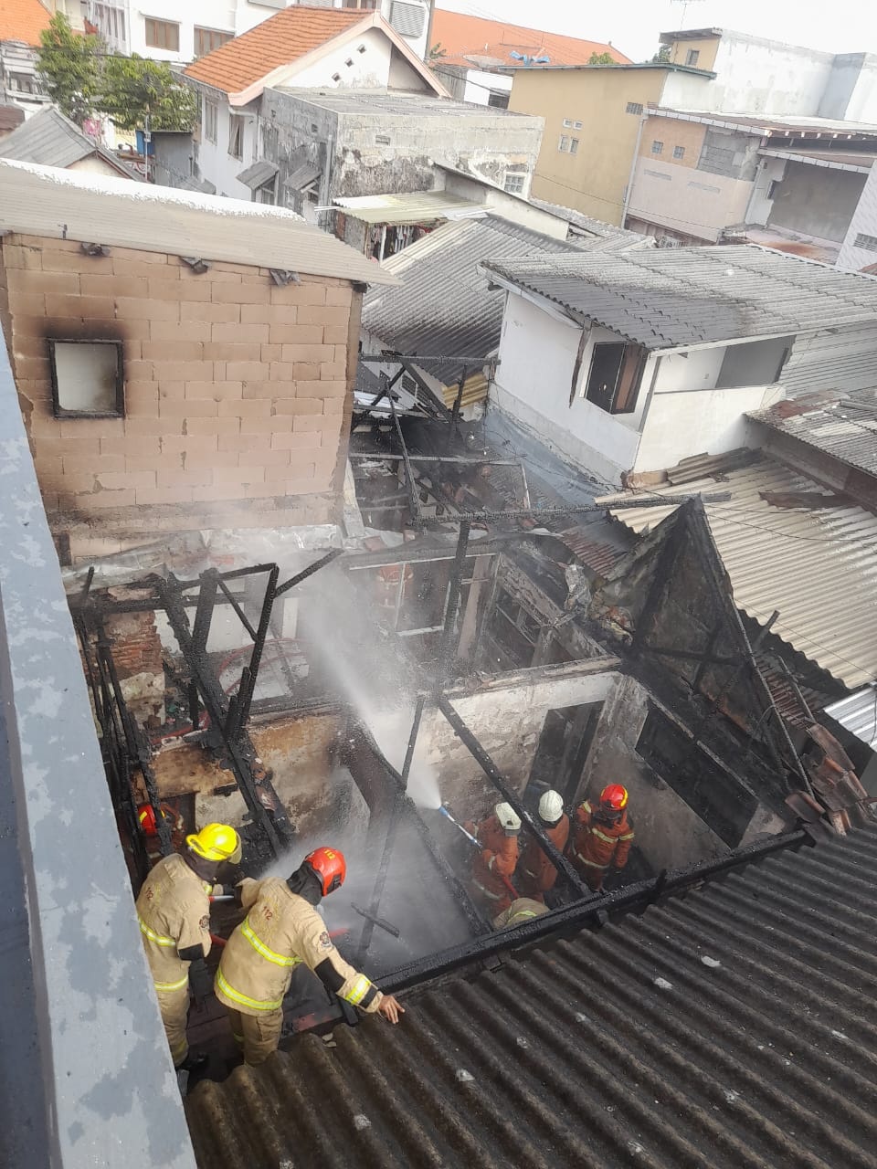 Petugas DPKP melakukan pemadaman dan pembasahan di rumah Jalan Kutai, Surabaya, Rabu (28/8).