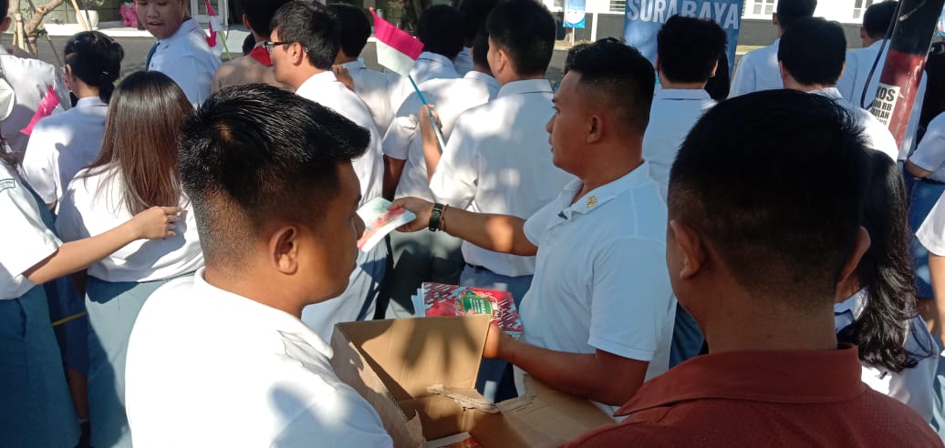 Tim Kepresidenan RI membagikan buku kepada siswa yang nenyambut kedatangan Presiden Jokowi di RS UPT Vertikal Kemenkes.