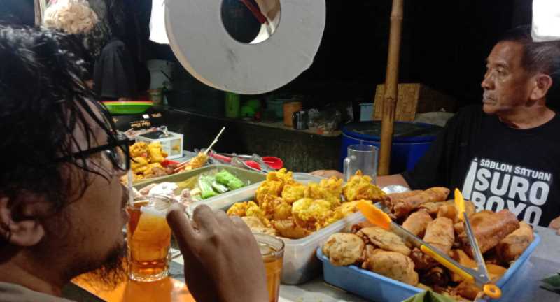 Cak Mis (kanan) di warung angkringan miliknya yang tak pernah sepi pembeli.