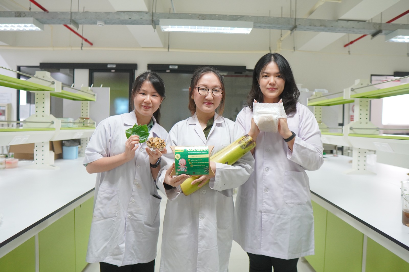 MUDAH TERURAI: Jeselyn Angelia, Nathasia Jasmine Benhady, dan Evelyn Darsono menunjukkan popok dari pelepah pisang dan daun sirih buatan mereka.