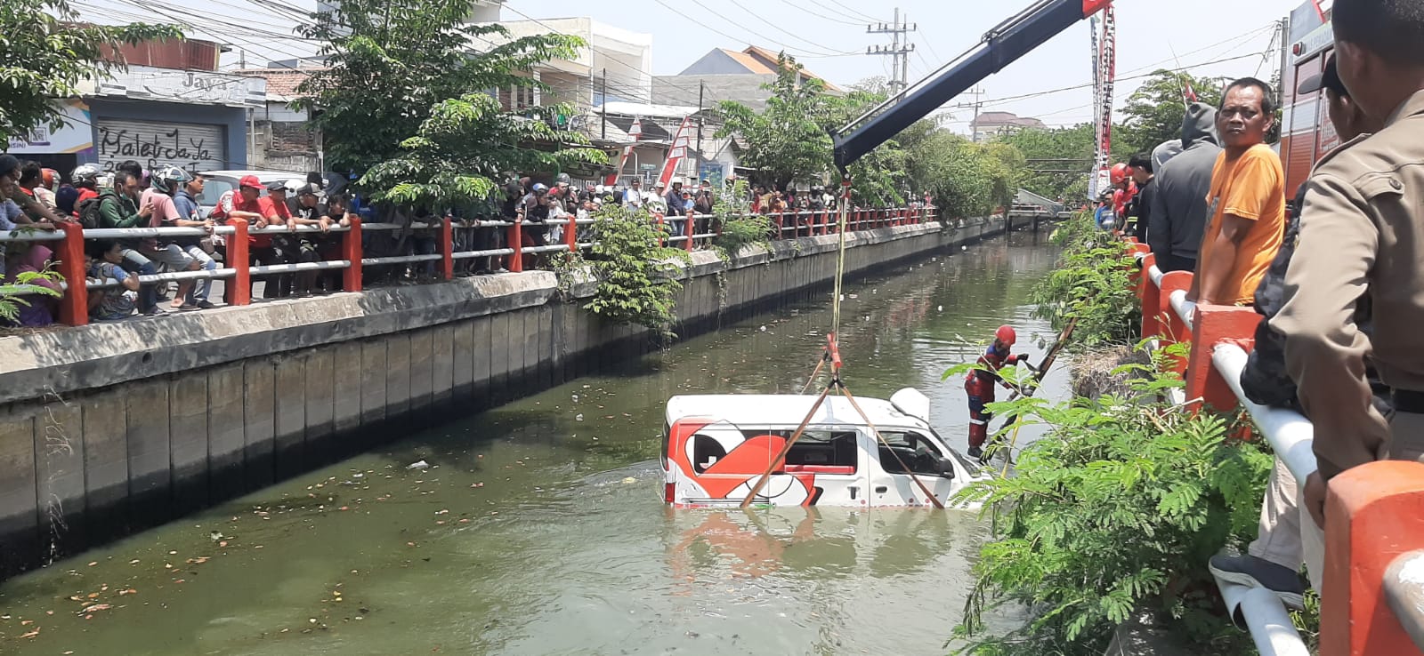 TERKEJUT: Kondisi mobil Wirawiri Suroboyo yang masuk ke sungai menjadi tontonan warga.