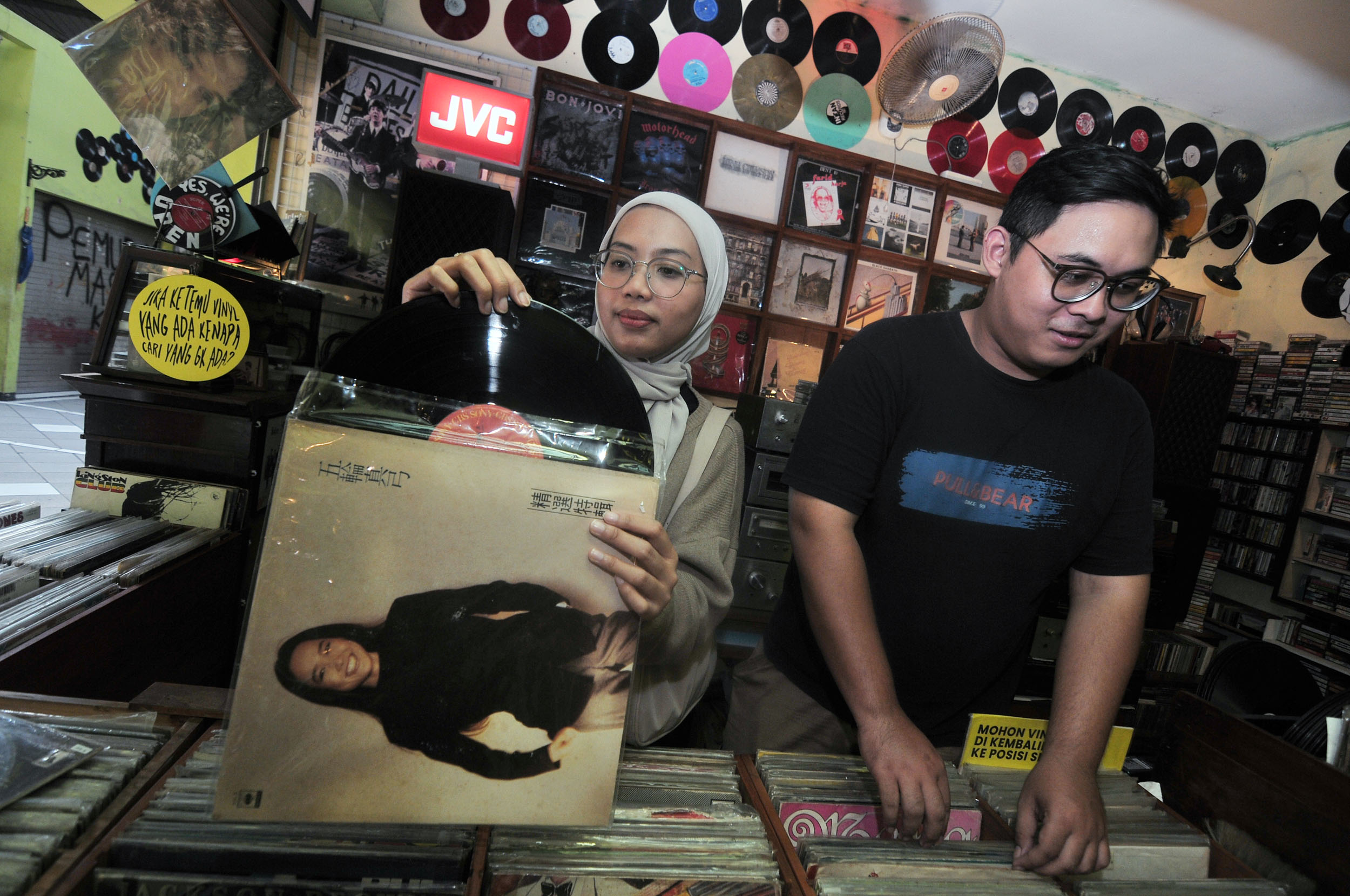 PENGGEMAR MUSIK: Nisa Andini (kiri) bersama Brillyan Rizqi, memilih piringan hitam yang merekam lagu-lagu lawas, di salah satu toko di Pasar Nostalgia Bratang, Surabaya, Minggu (29/9).