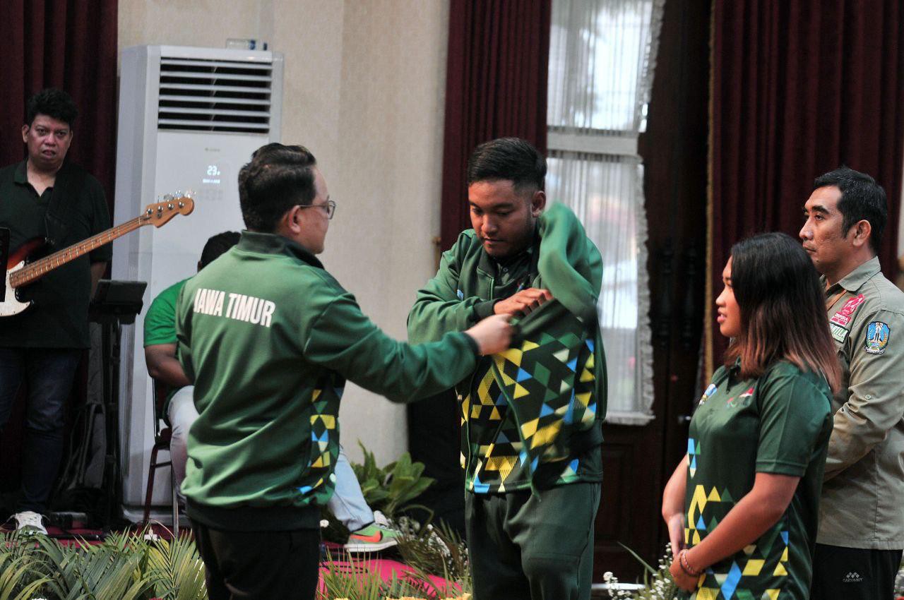 Penjabat Gubernur Adhy Karyono menyematkan atribut kontingen Jatim.