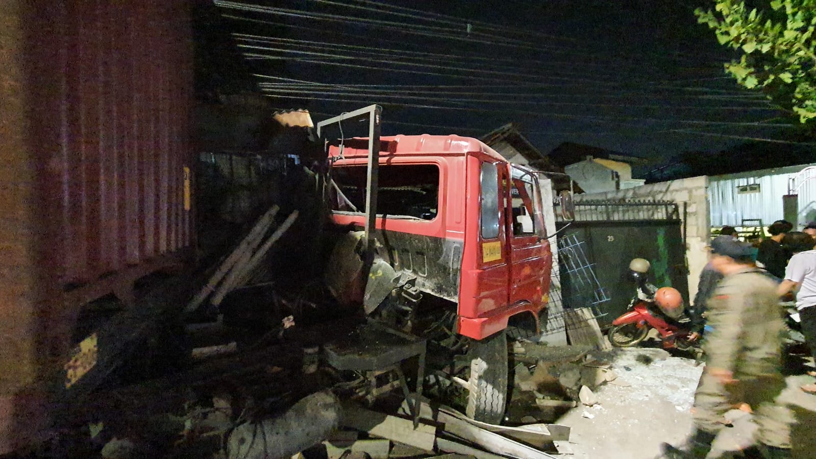 Truk trailer nopol S 8081 UP yang disopiri Wijaya Kusuma menabrak pagar makam dan pagar rumah warga Jalan Mastrip, Surabaya Rabu malam (2/10). (IST)