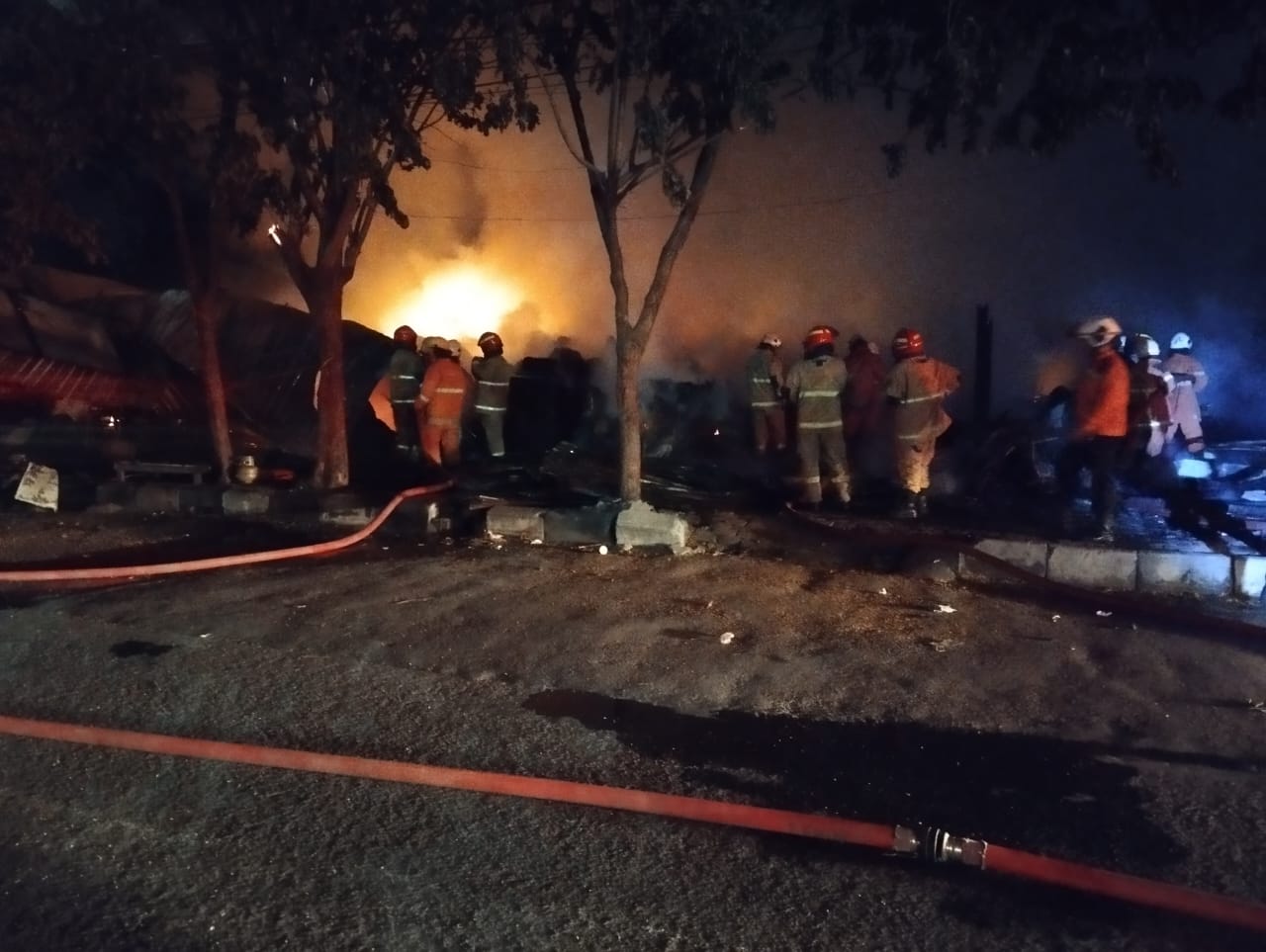 Petugas memadamkan api yang melalap warung di kawasan Kenjeran Surabaya. (IST)