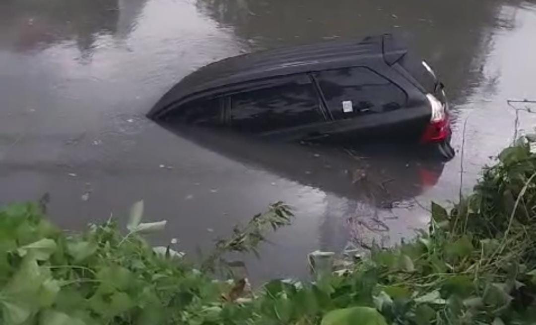 Mobil tercebur akibat terseret pohon tumbang di Jalan Dharmahusada Indah, Surabaya. (IST)