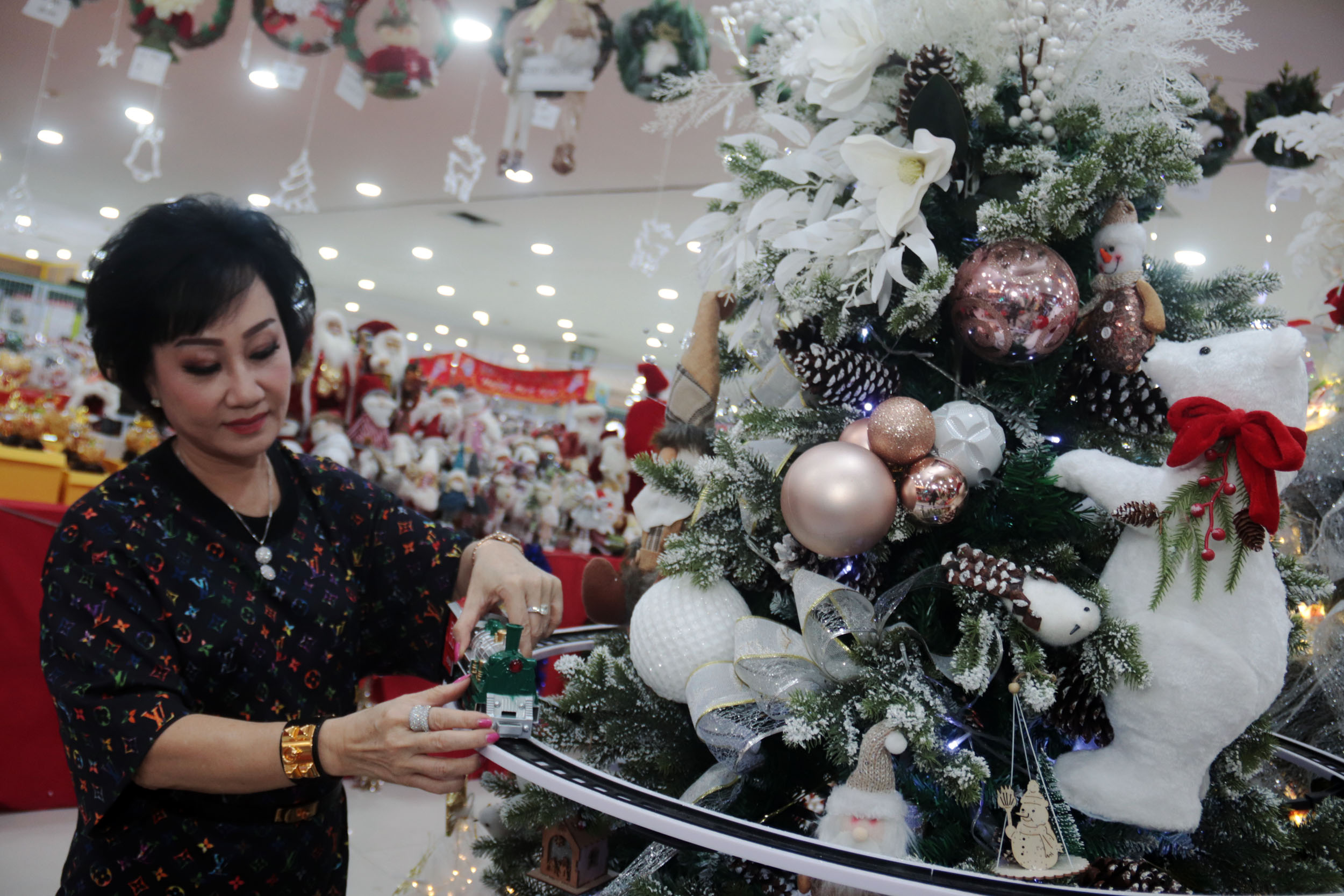 PERNAK PERNIK: Sujani, penjual aksesoris Natal di Pasar Atom Mall Surabaya menunjukkan kereta api mainan pada pohon Natal yang menjadi salah satu koleksi terbaru.