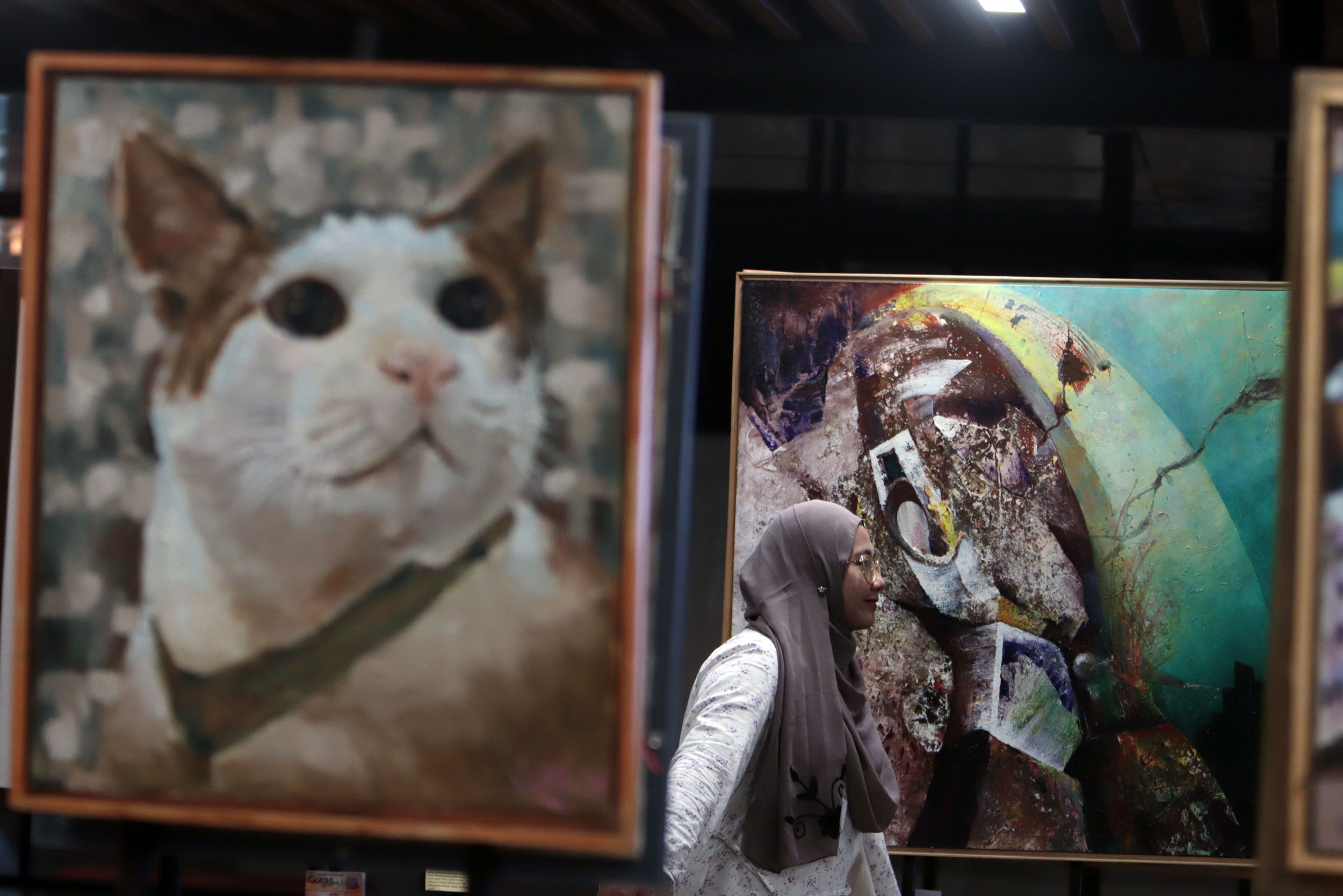 PAMERAN AKHIR TAHUN: Pengunjung mengamati lukisan-lukisan karya perupa yang tergabung dalam Drawing Community dengan judul Jejak Akhir Tahun di Basement Alun-Alun Surabaya.