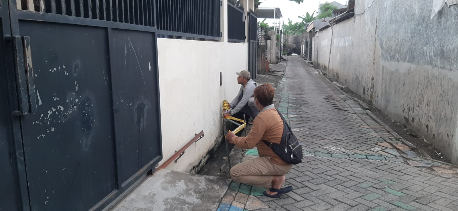 TKP: Anggota Reskrim Polsek Wiyung memasang garis polisi di selokan lokasi terceburnya korban di Jalan Babatan II F, Wiyung Surabaya.
