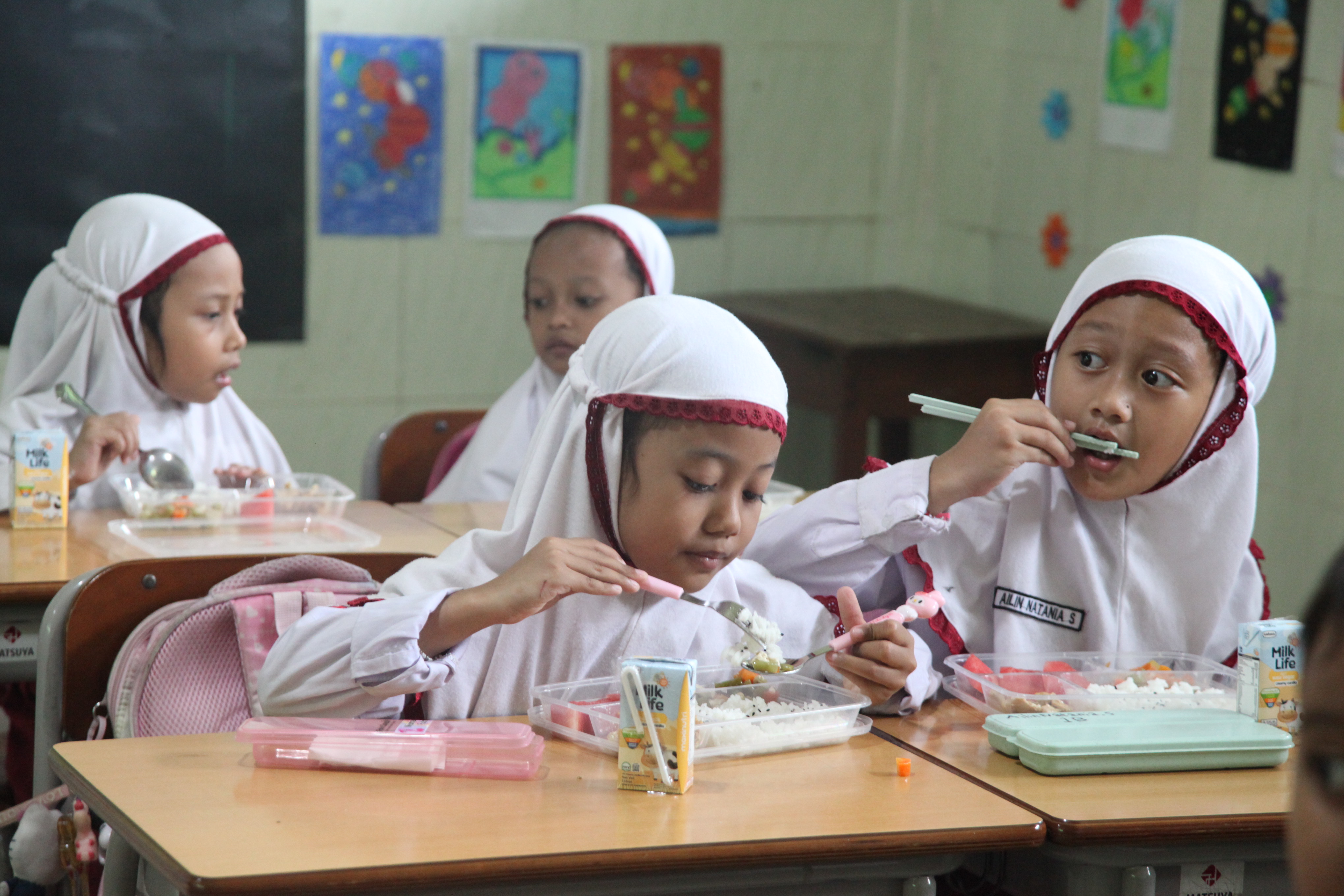 Sejumlah siswa menikmati makan bergizi gratis di di SD Taqoma, Jemur Andayani, Wonocolo, Surabaya.