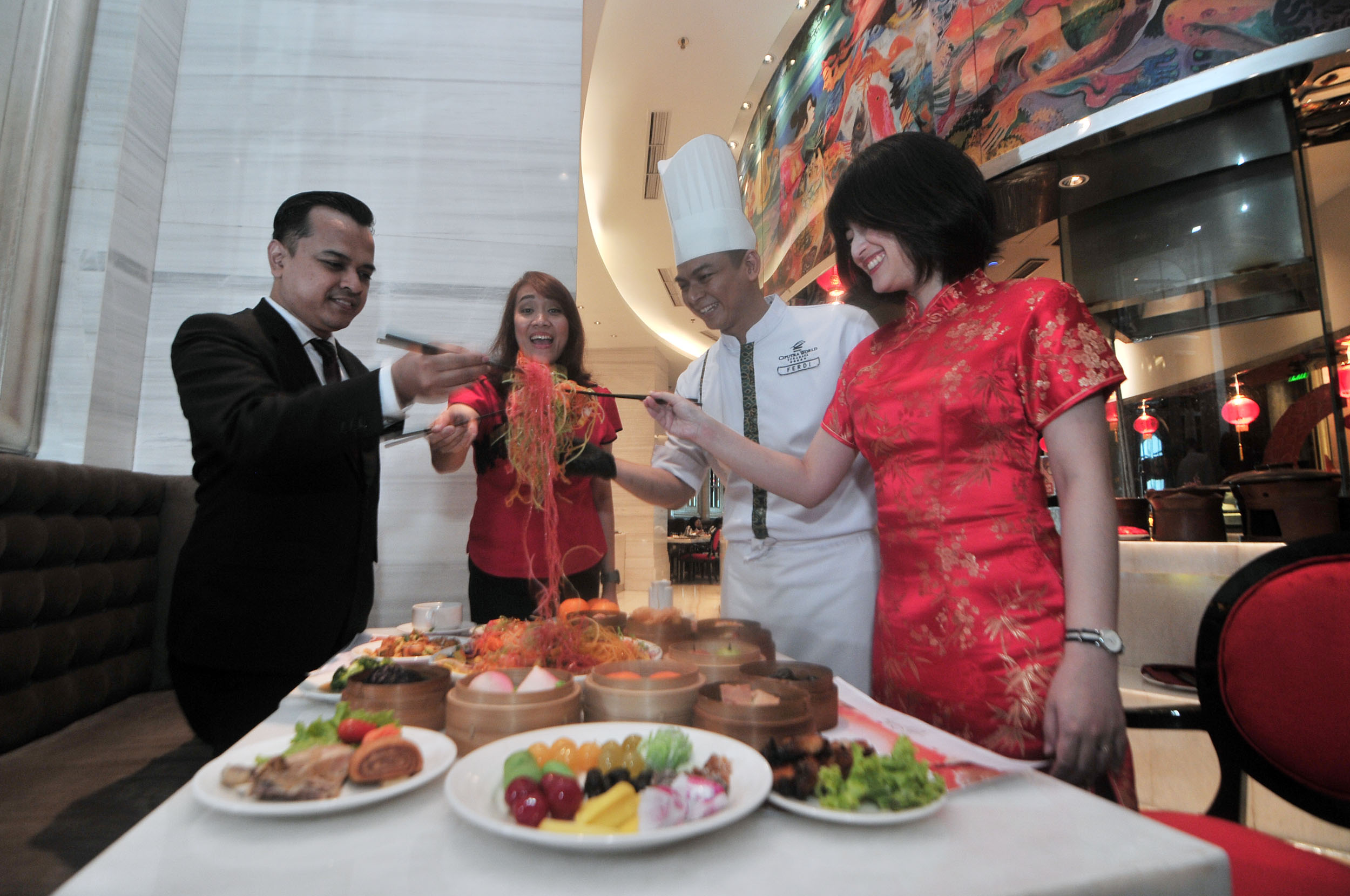 KHAS TIONGHOA: Amey bersama rekannya menikmati Yee Sang dengan cara diangkat dengan sumpit beramai-ramai di Hotel Ciputra World Surabaya, Selasa (14/1).