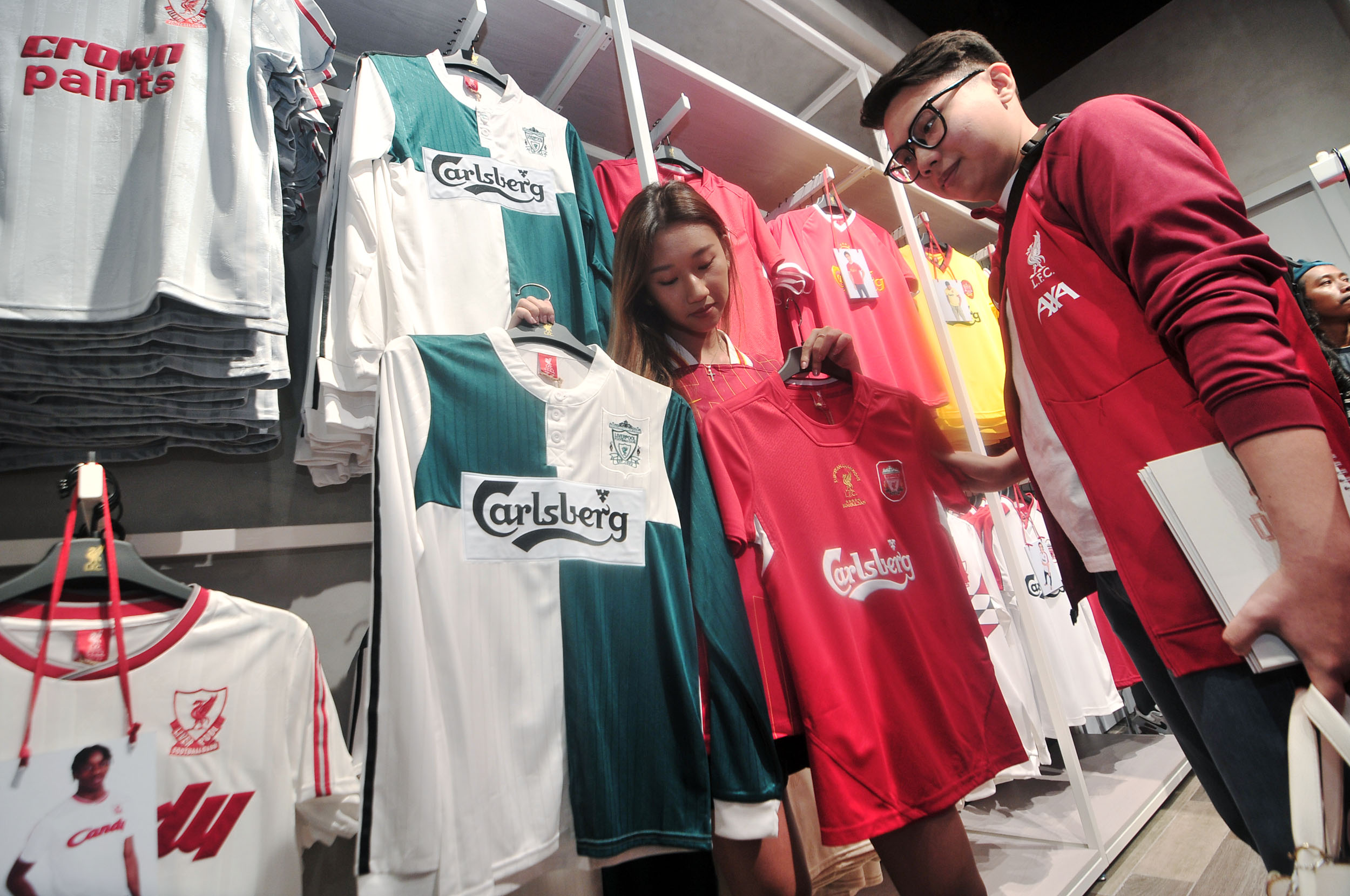 Dua orang pengunjung memilih-milih jersey klub sepak bola yang digunakan klub pada masa lalu dan memiliki sejarah sendiri, di Liverpool Store, Pakuwon Mall Surabaya.