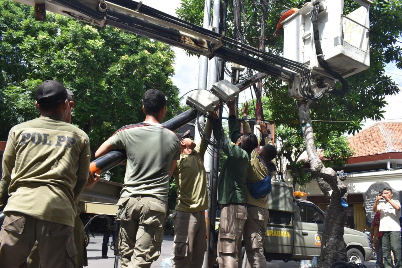 Petugas Satpol PP menertibkan kabel utilitas yang melanggar di Surabaya.