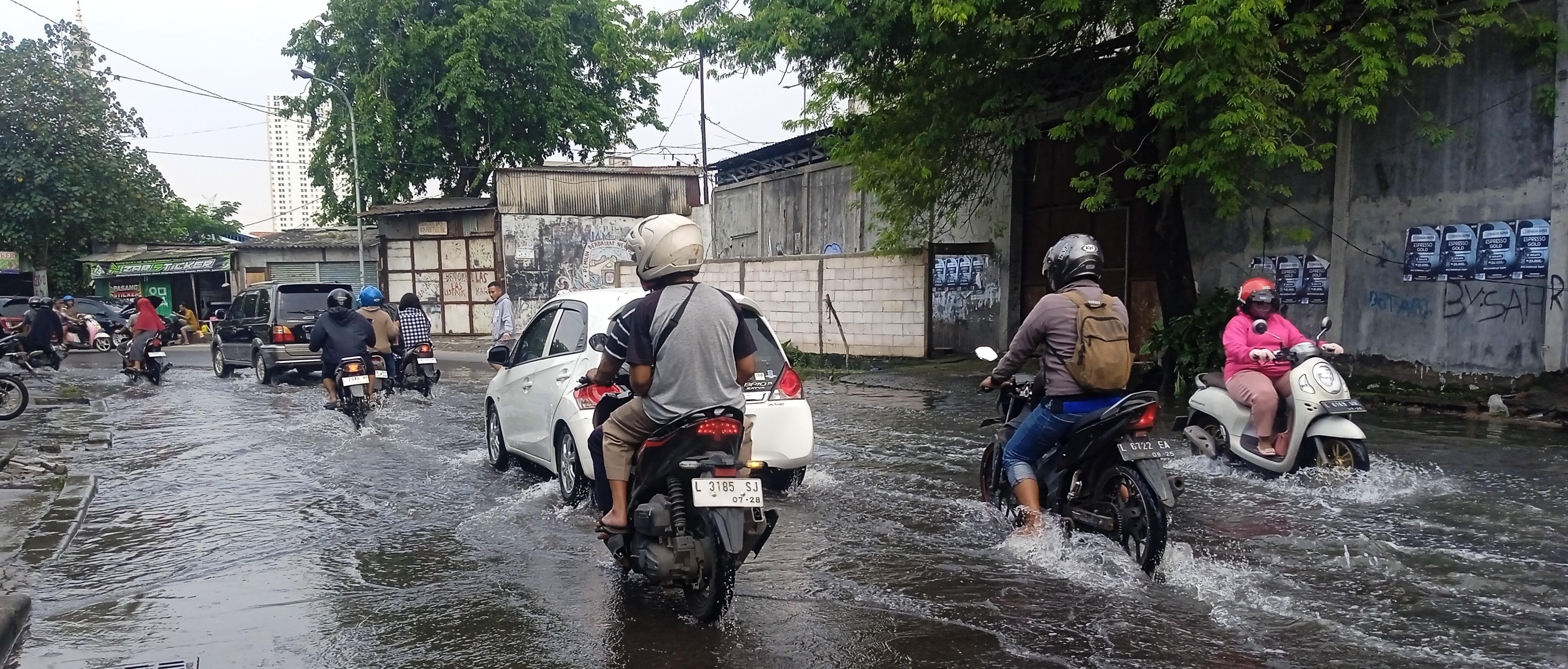 BELUM SURUT: Pengendara kendaraan bermotor menerjang genangan air di kawasan Tambak Mayor, Surabaya.